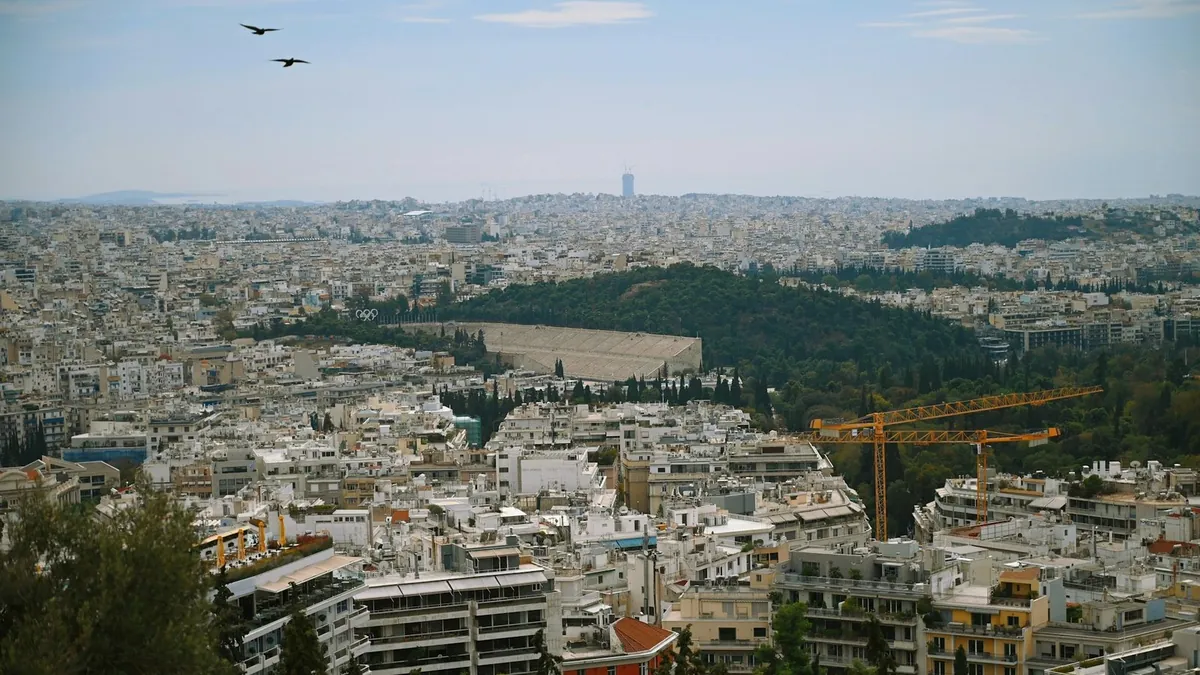 Πανοραμική θέα της Αθήνας με το Παναθηναϊκό Στάδιο και γερανούς οικοδομής